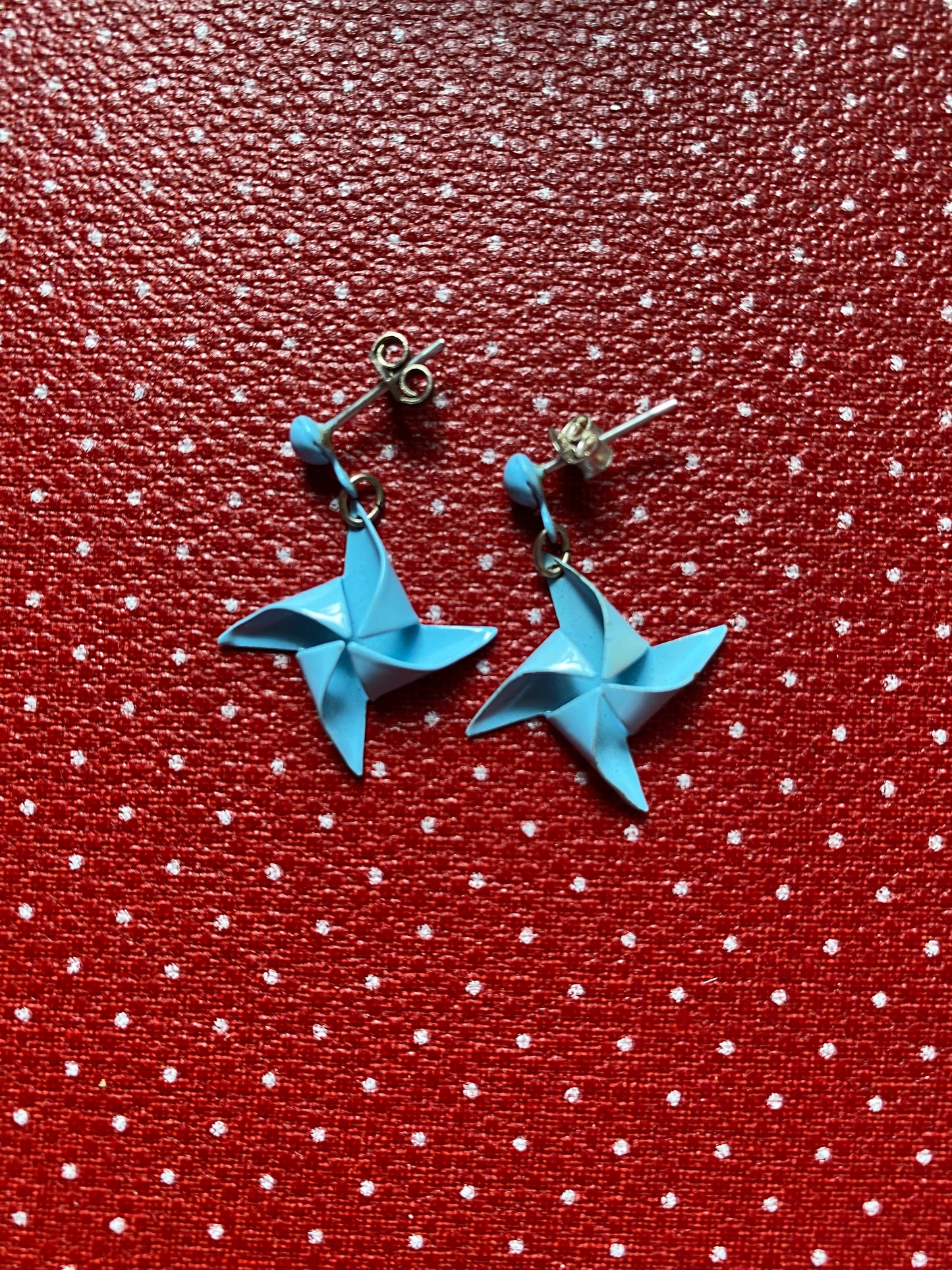 Authentic 80s metal Blue star-shaped earrings on a red retro fabric background