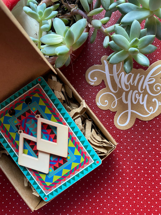 Colorful geometric card with 80s earrings diamond shape  in a box with a 'thank you' card on a red retro polka dot background