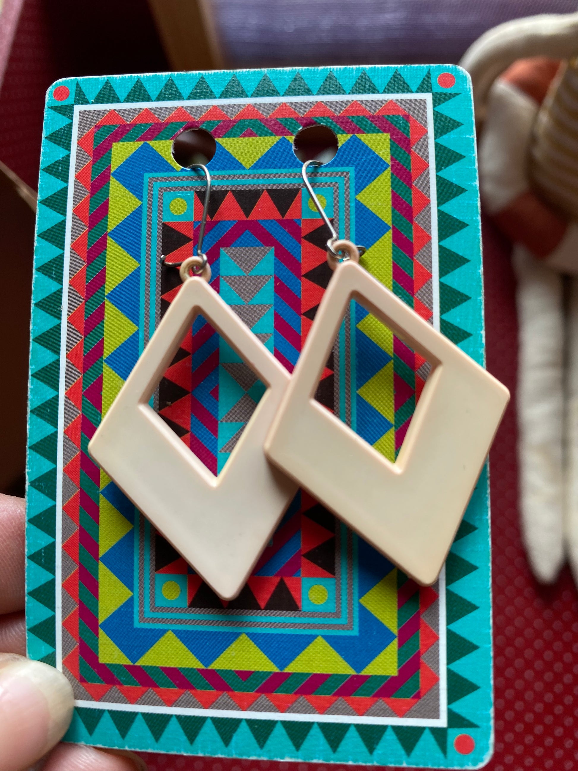 Authentic 80s Beige geometric earrings on a colorful patterned card held by a hand.