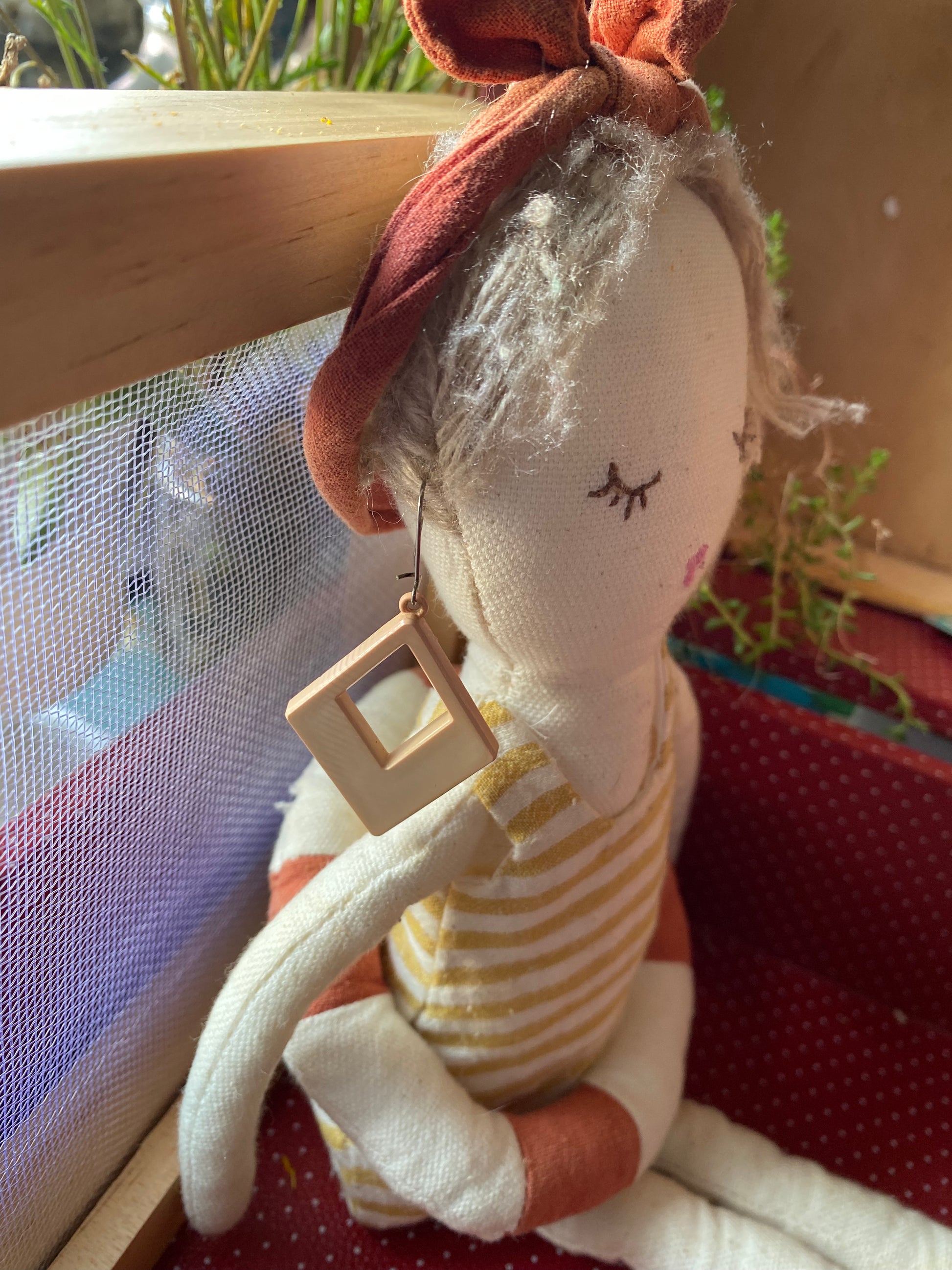 Modelling a pair of 80s earrings wearing with a bow and striped outfit on a red surface