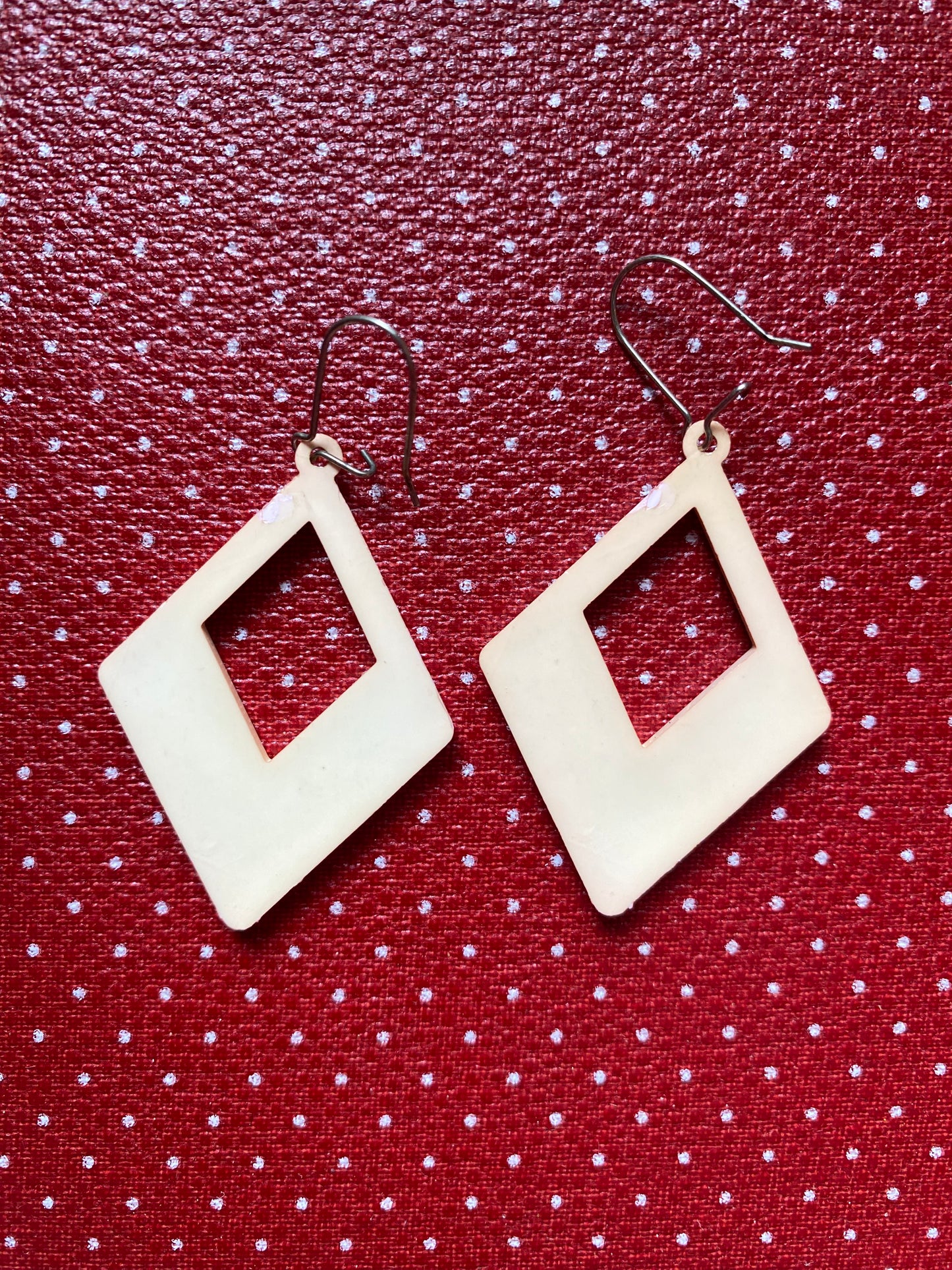 Authentic 80s diamond-shaped earrings on a red polka dot background