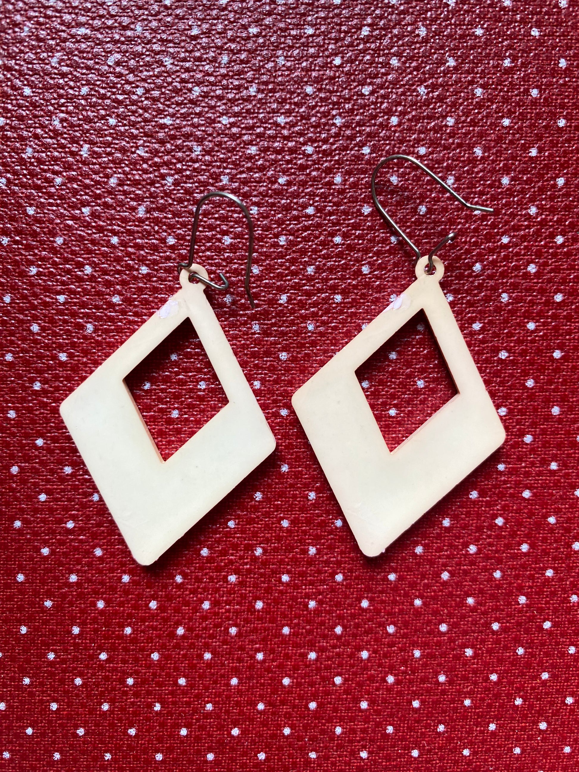 Authentic 80s diamond-shaped earrings on a red polka dot background
