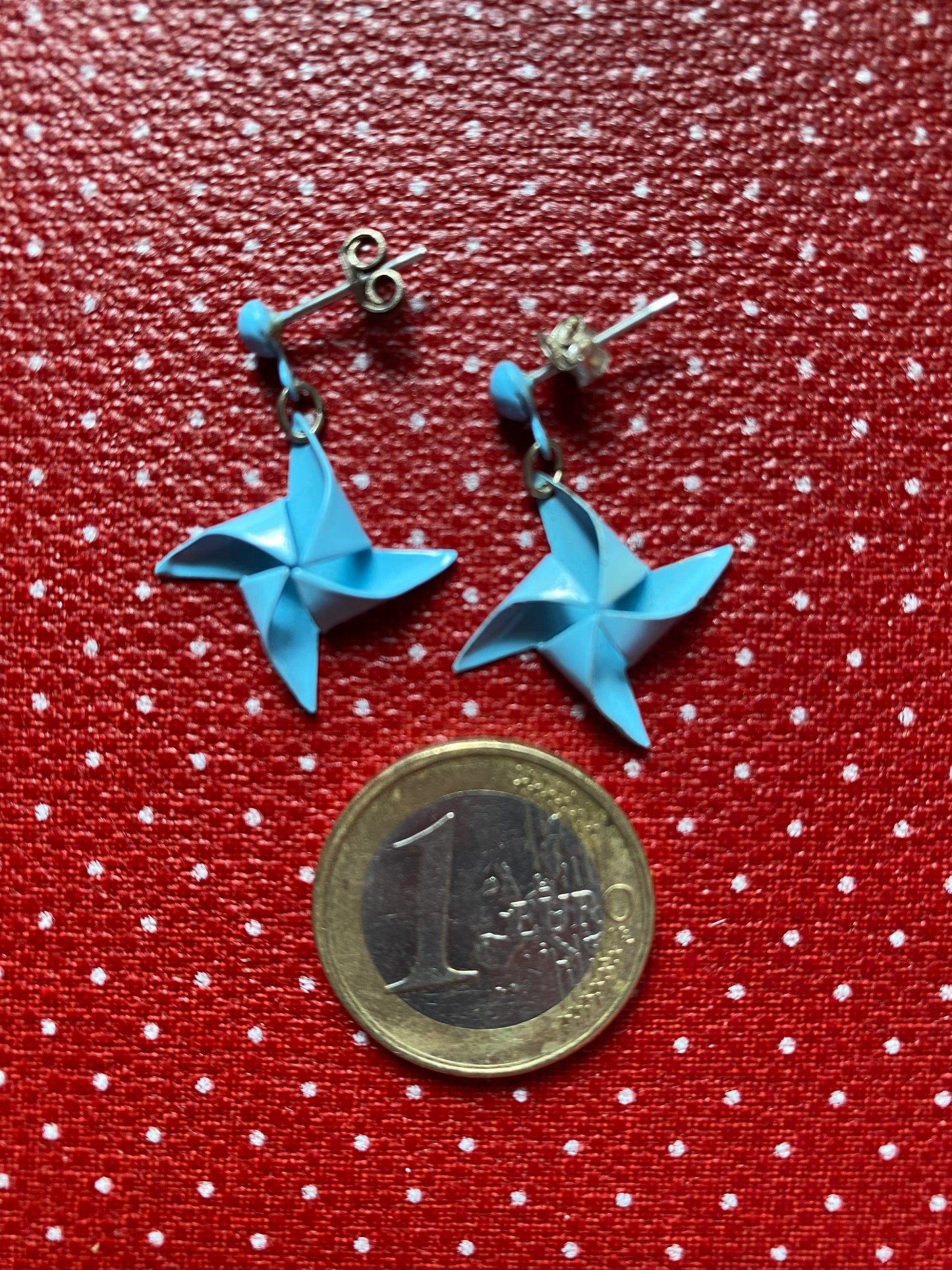 Authentic 80s metal Blue origami star earrings on a red polka dot background with a coin for scale.