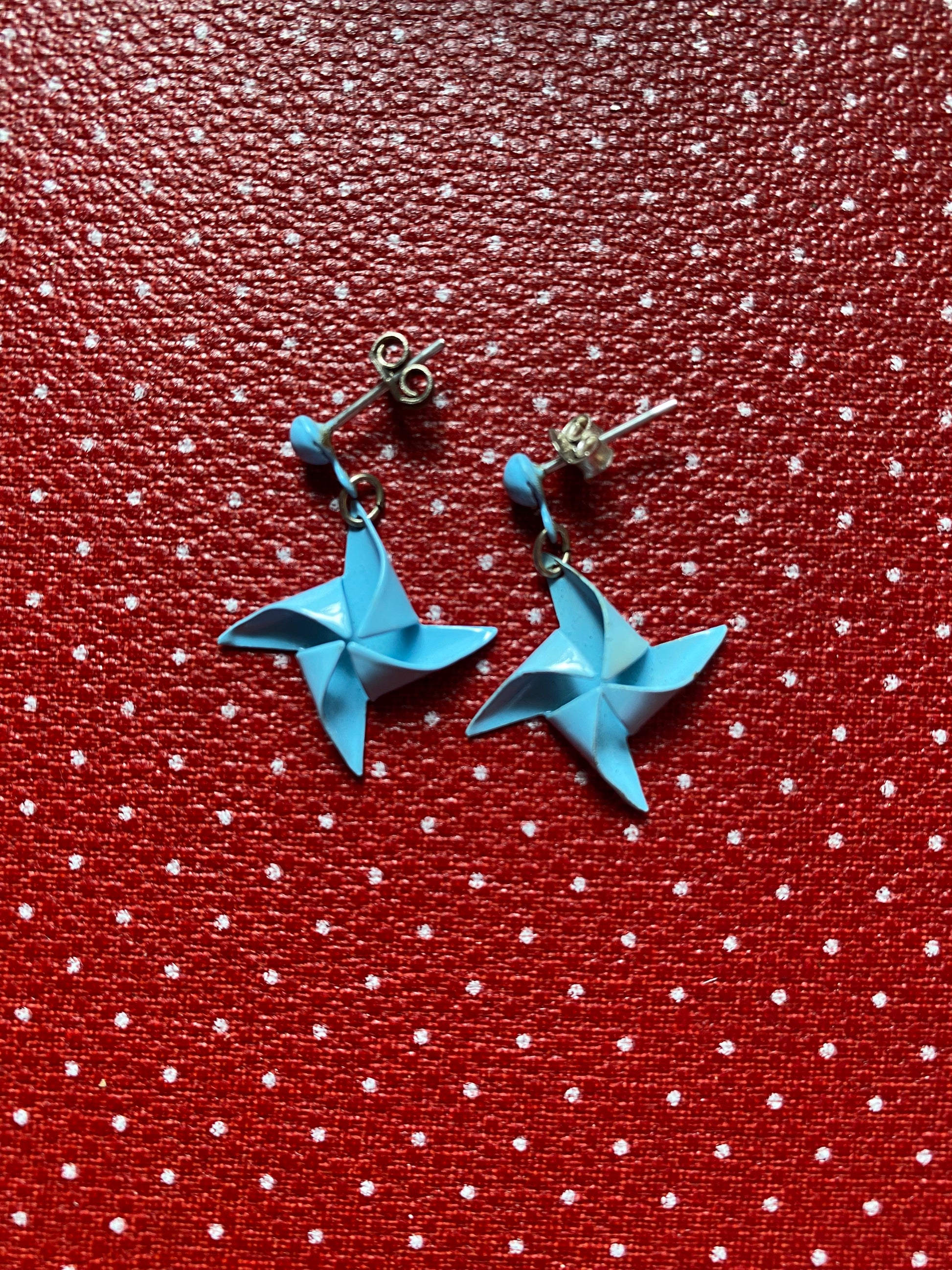 Authentic 80s metal Blue star-shaped earrings on a red retro fabric background 