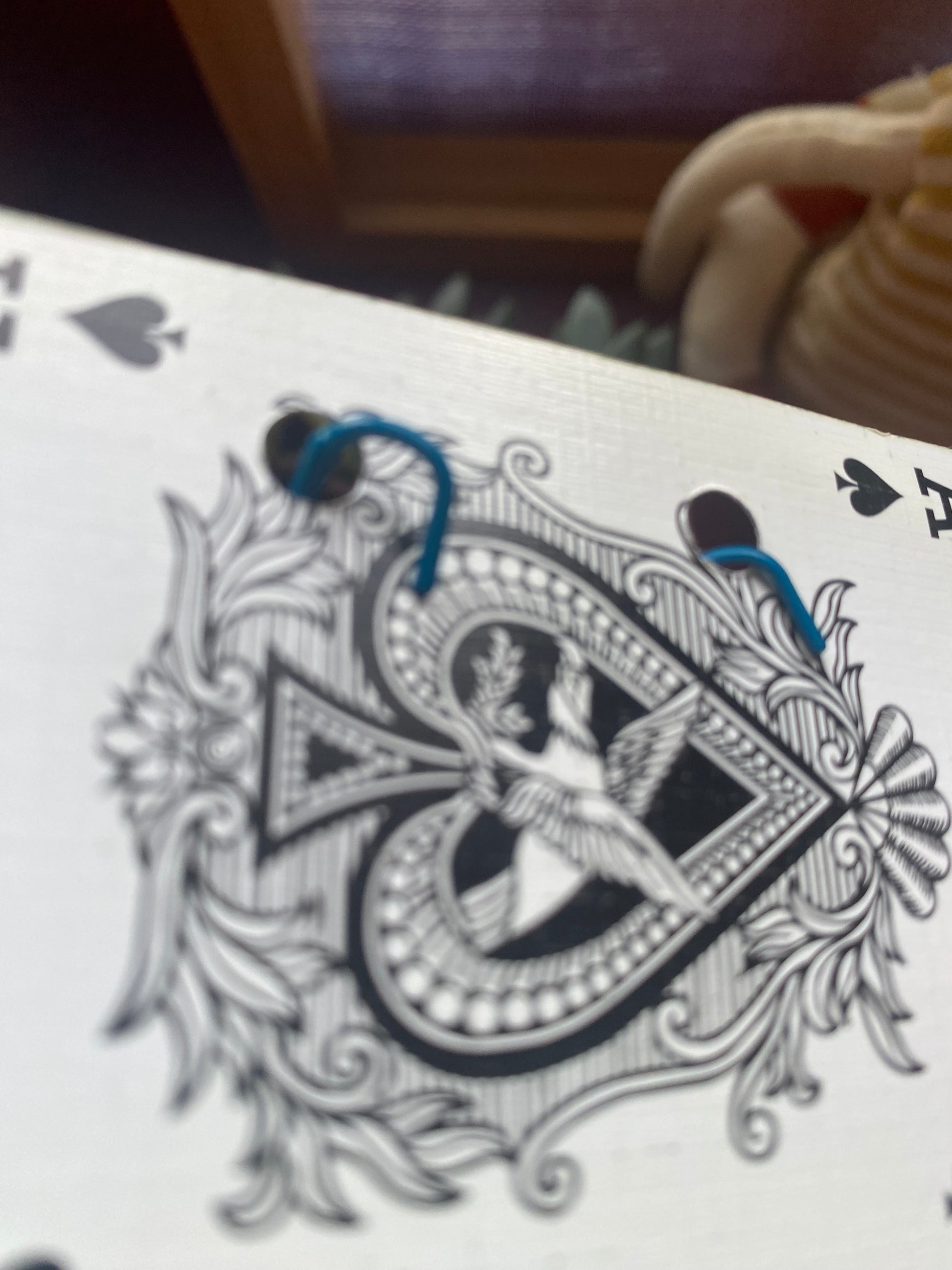 Close-up of a playing card with decorative design and blue hooks
