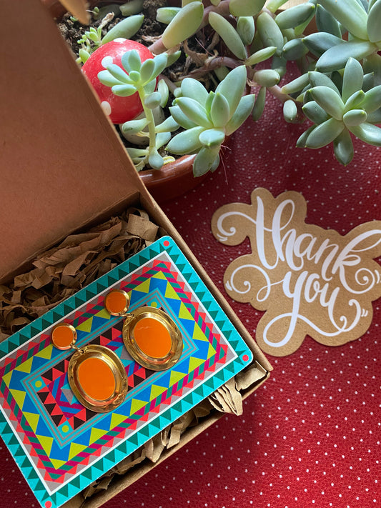 80s authentic earrings, potted succulent, and 'thank you' card on a red surface.