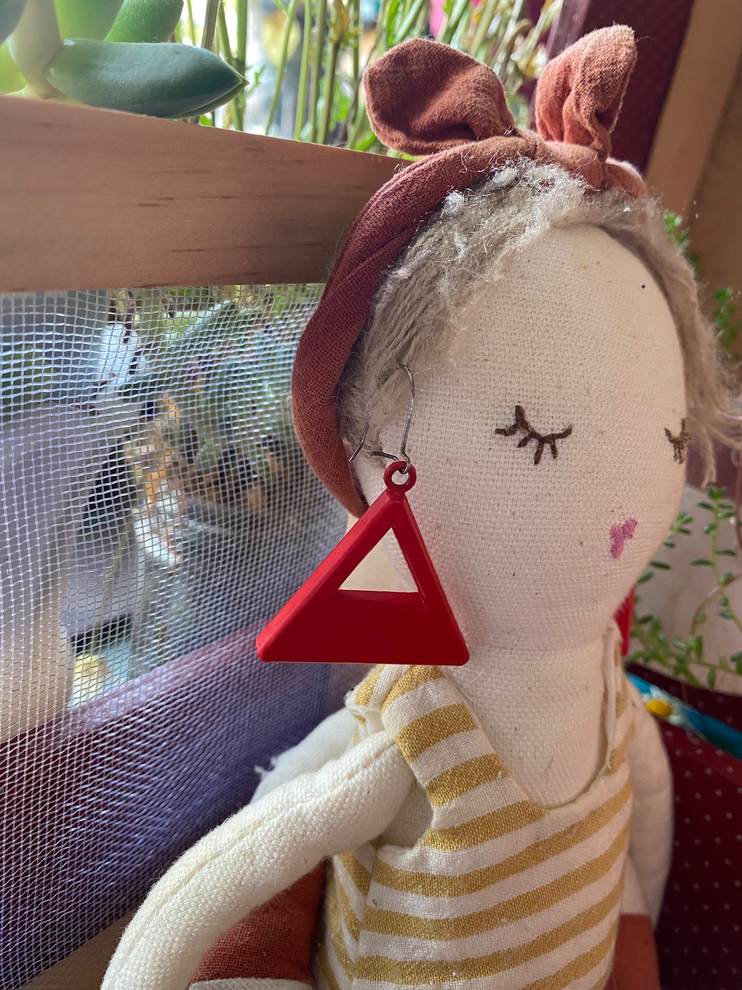 Textile doll model with a pair of 80s authentic red triangle earring in front of a window