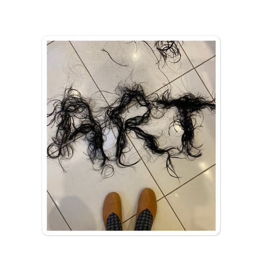 Photography of freshly cut hair spelling ART on floor with feet in view