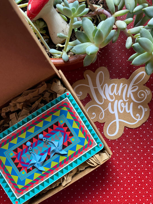 Colorful card with geometric design and a small authentic 80s earrings, placed on a red retro surface with 'thank you' card.