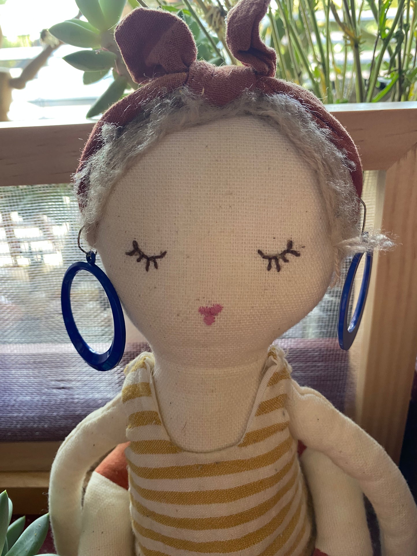 Textile doll model the blue 80s hoop earrings in a home setting