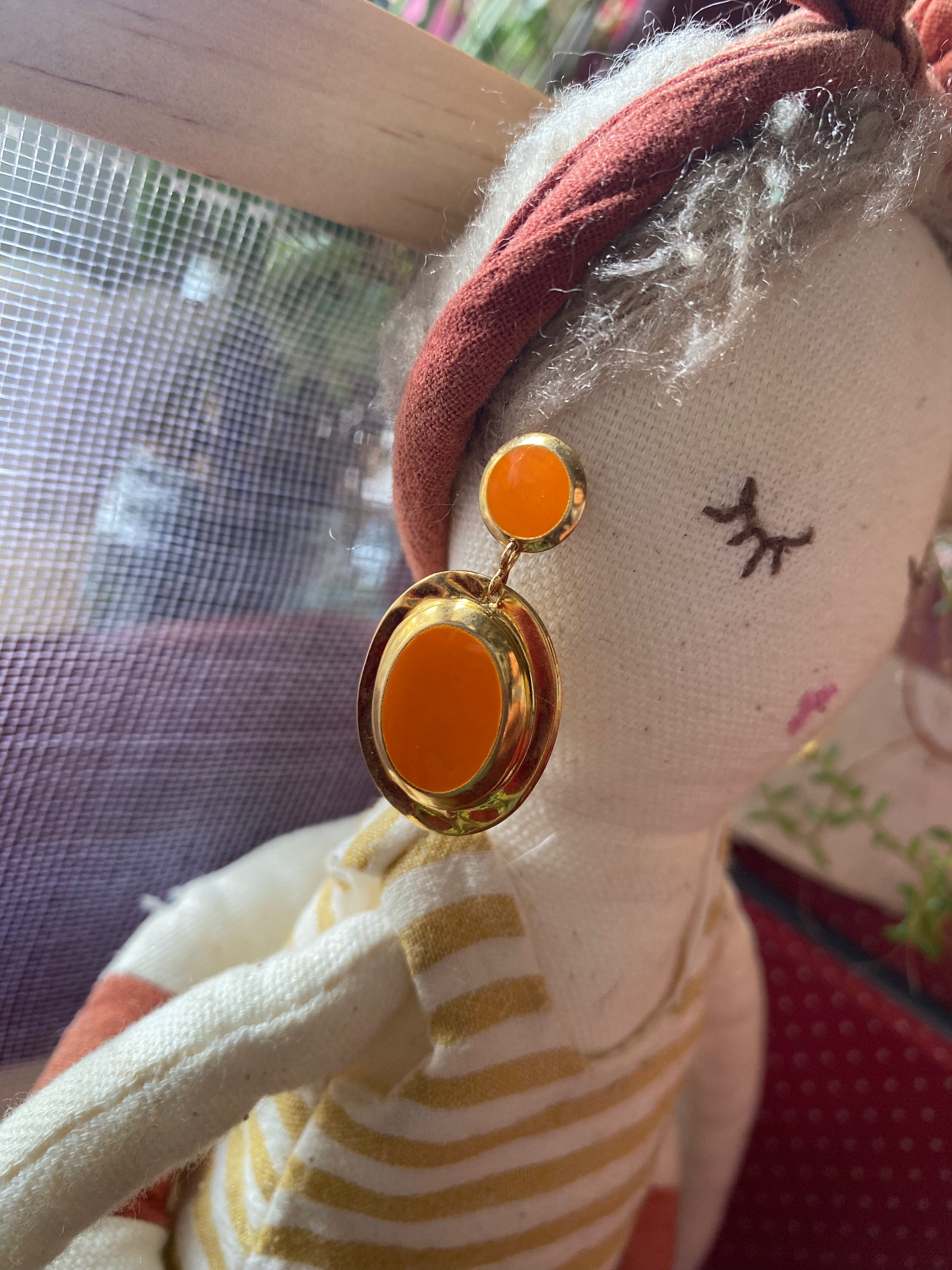 Close-up of a doll wearing gold like earrings / orange