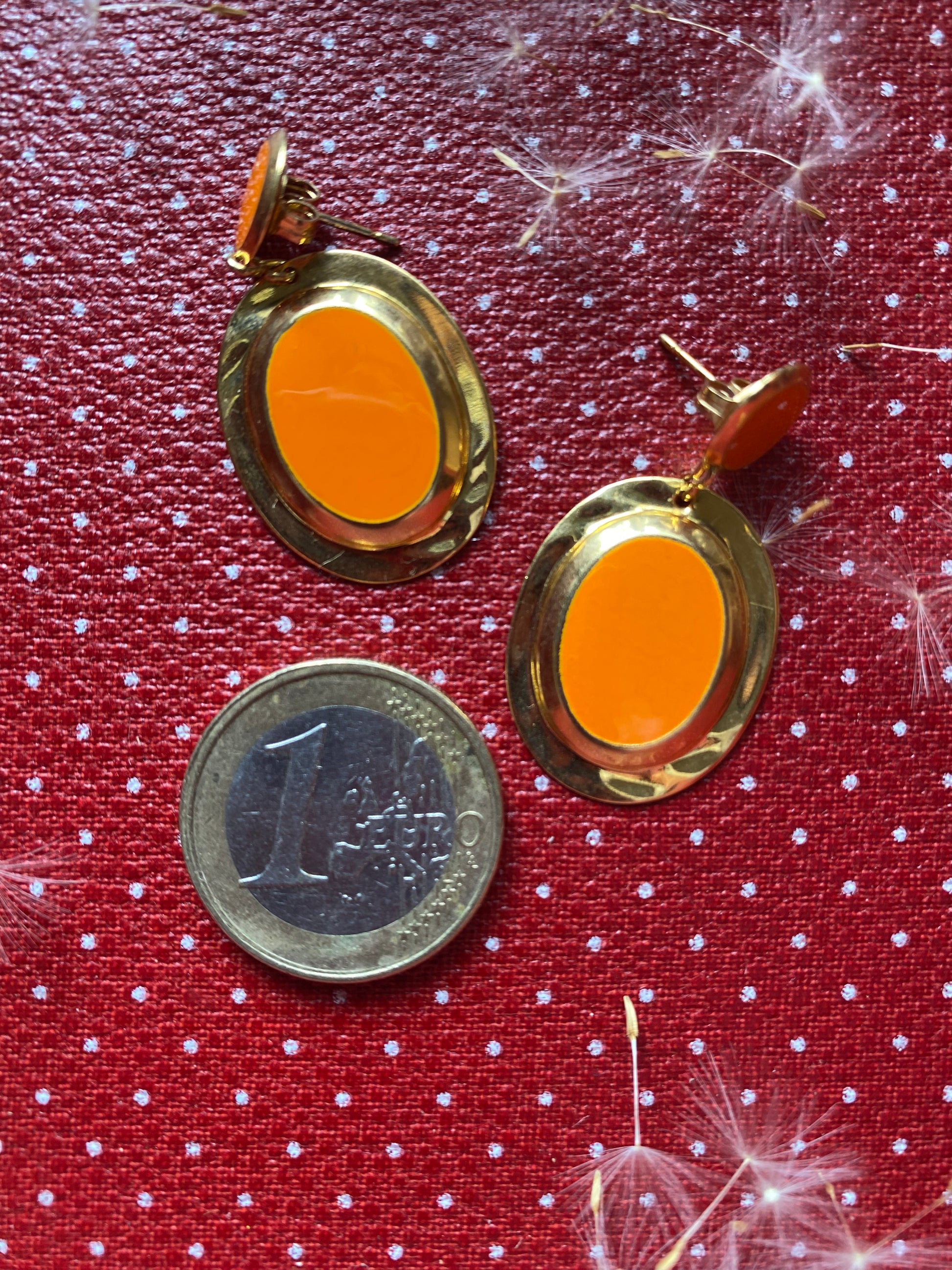 Gold like 80s earrings with orange on a red polka dot background