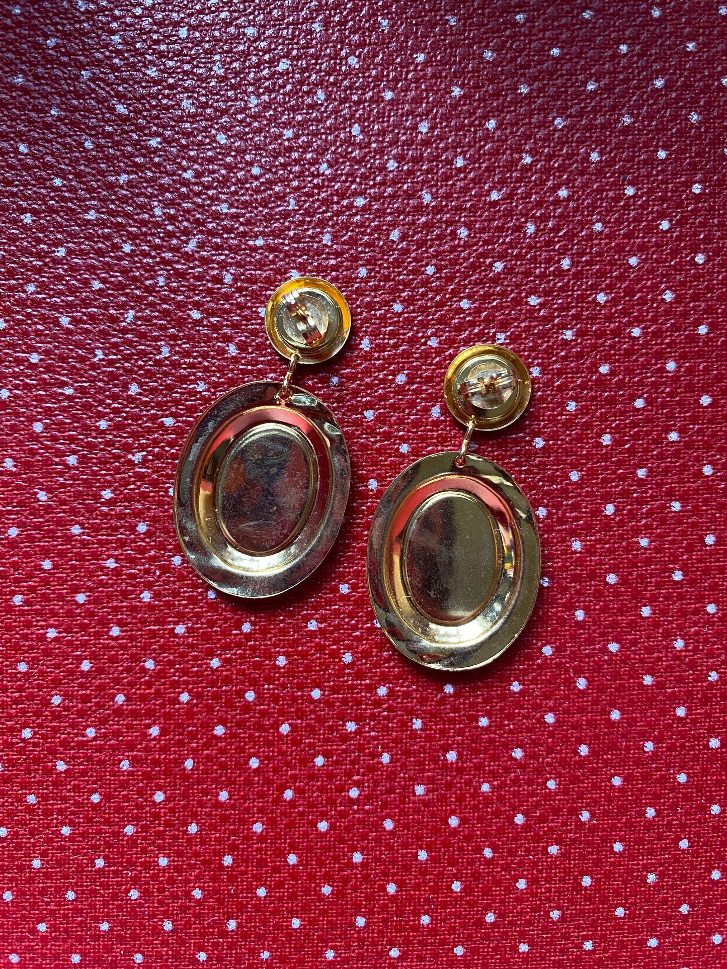 Gold like 80s earrings on a red polka dot fabric background