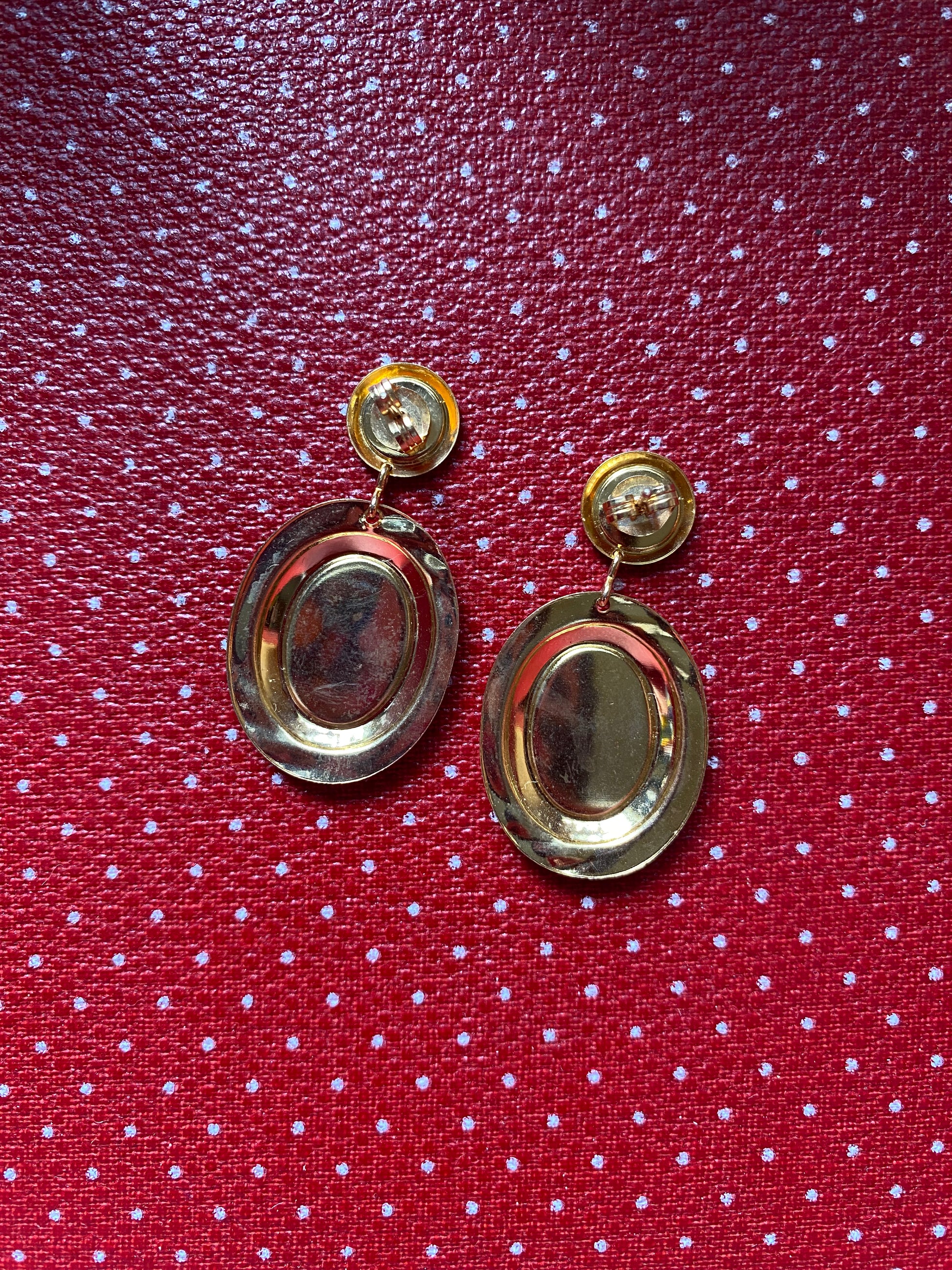 Gold like 80s earrings on a red polka dot fabric background