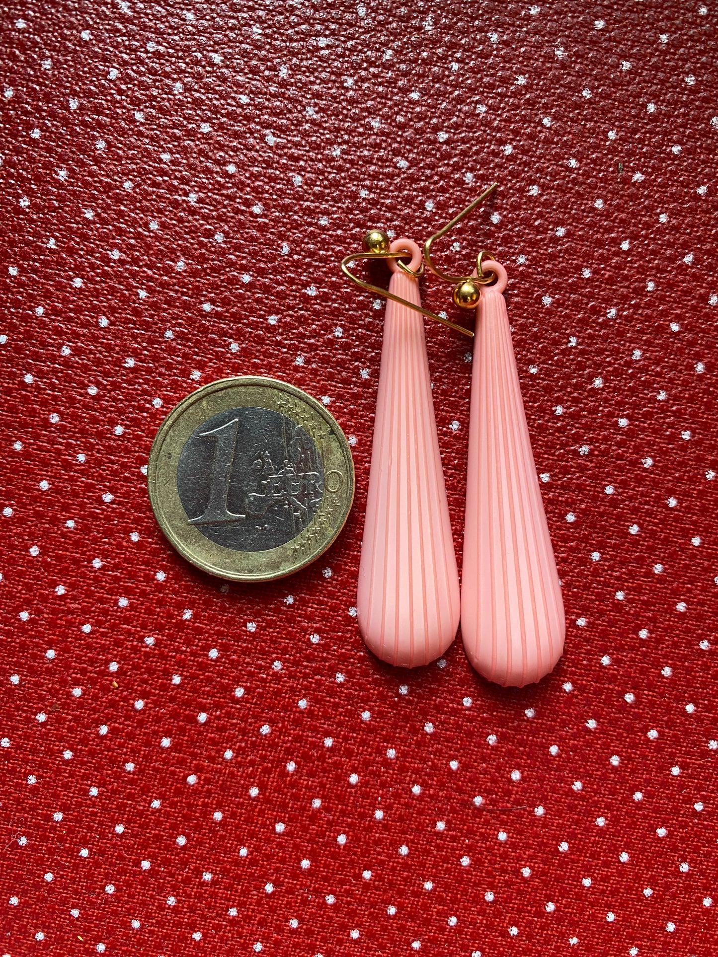 Pink authentic 80s  teardrop earrings on a red polka dot background with a coin for scale.