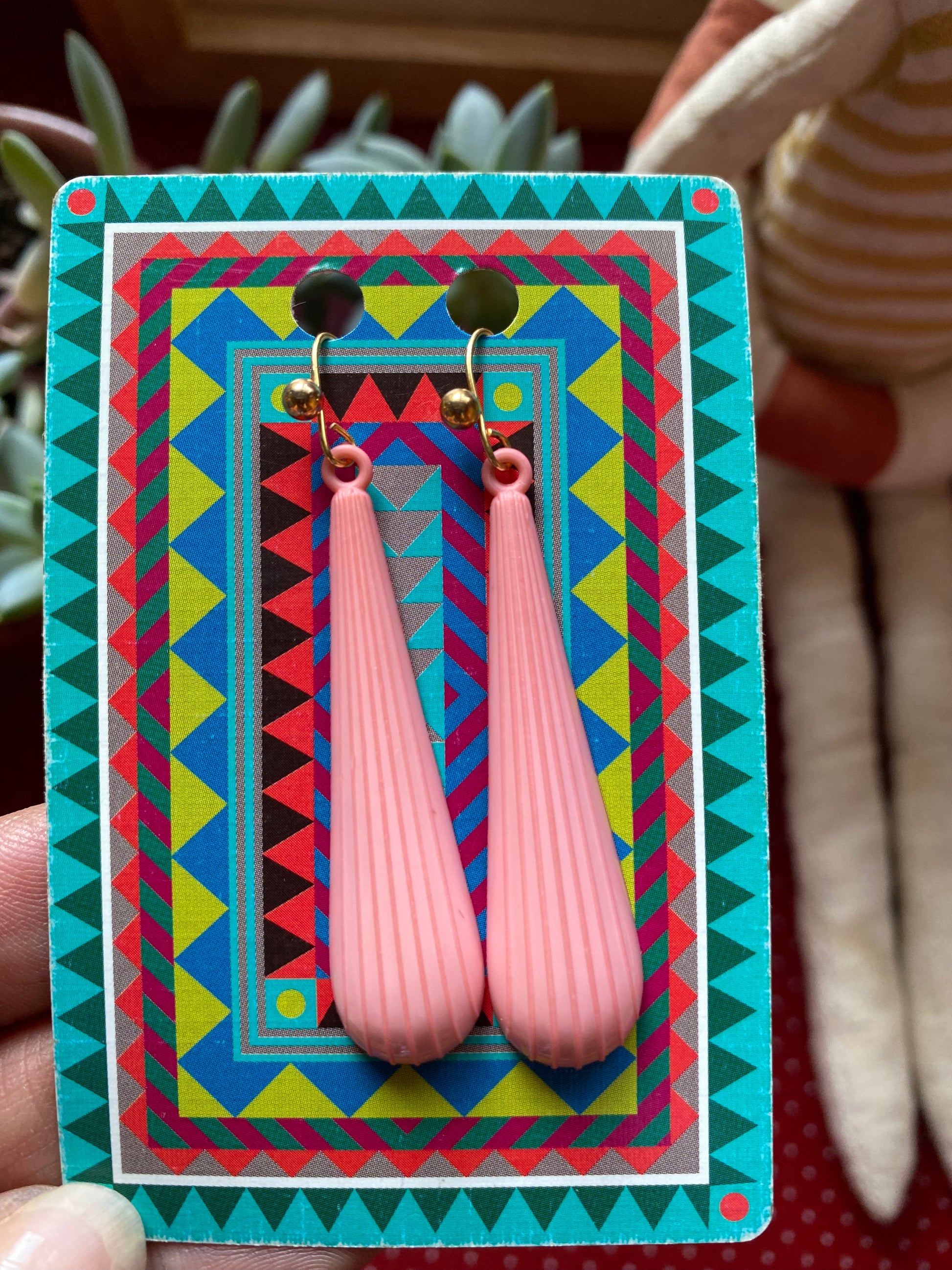 Pair of 80s pink earrings on a colorful patterned card