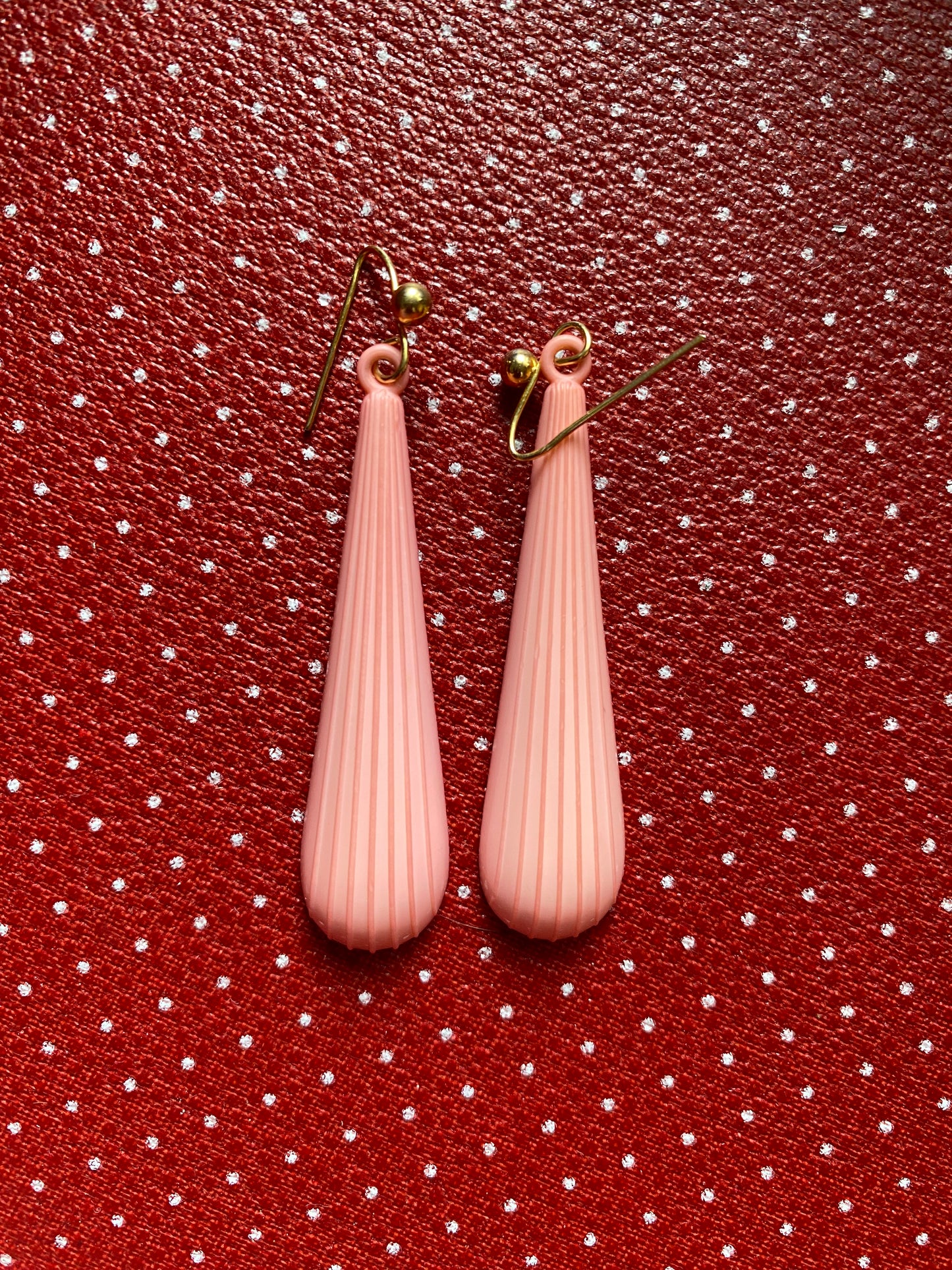 Pink authentic 80s teardrop earrings on a red polka dot background