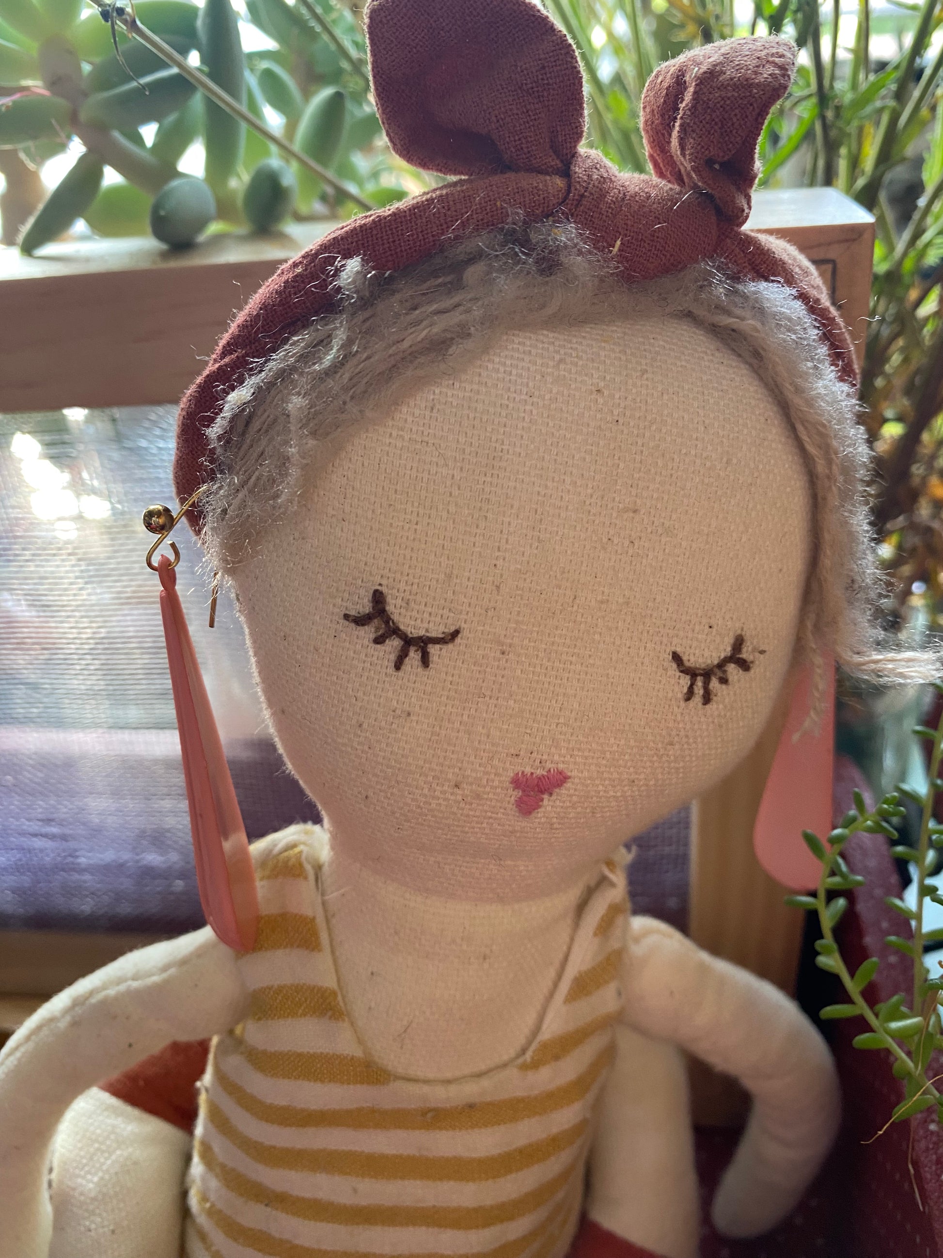 Textile doll modelling the teardrop  earrings and wearing a striped dress in a natural setting