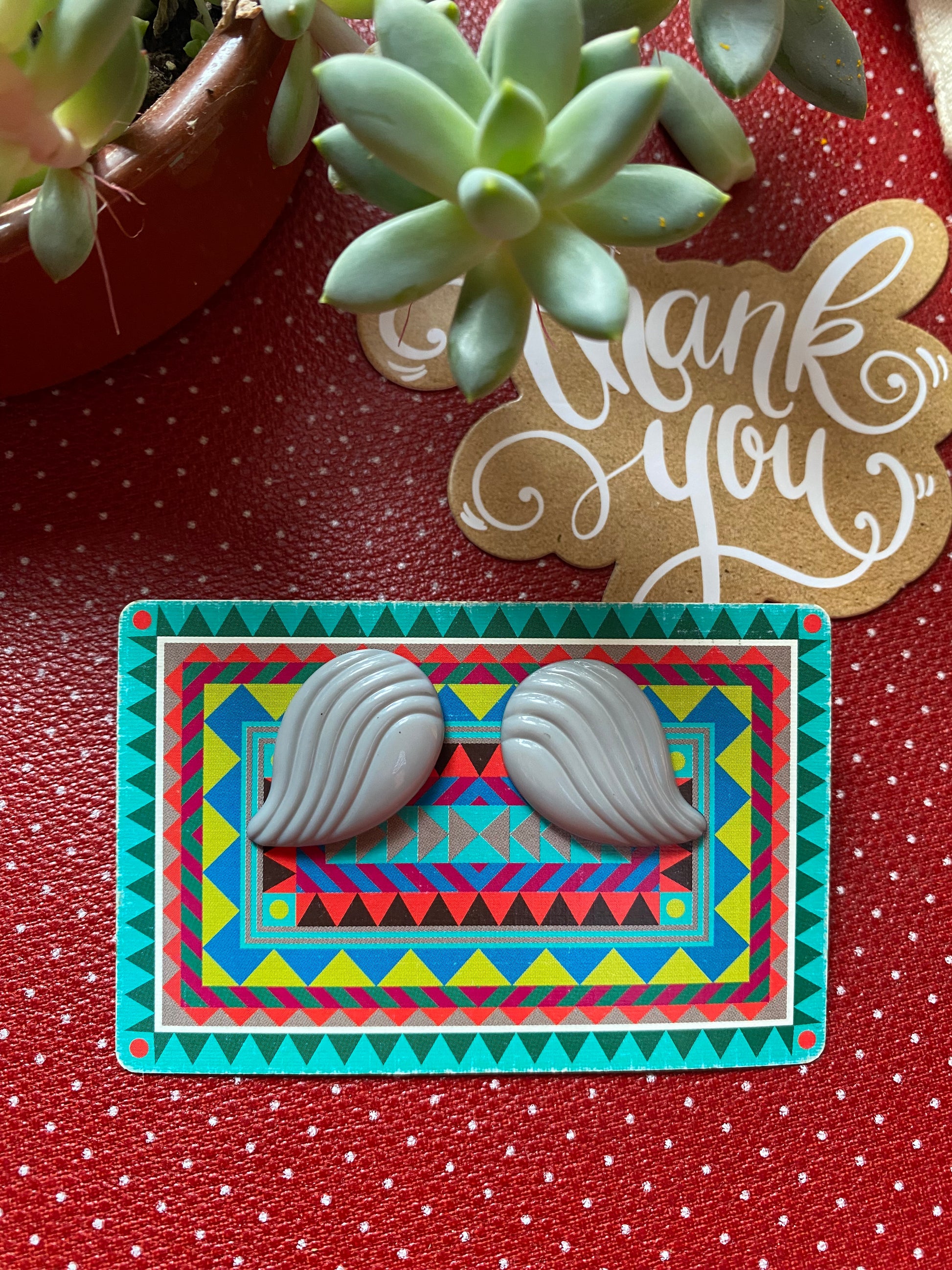 Decorative card with geometric pattern and a pair of grey authentic 80s shell like design earrings on a red background with 'Thank you' card.