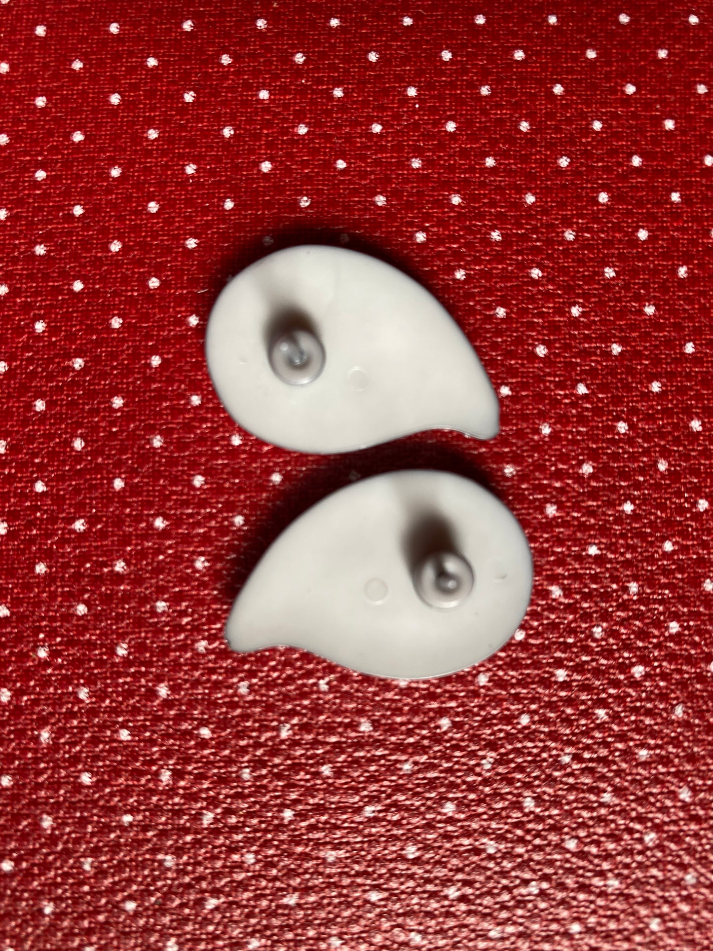 Showing the back of the earrings on a red fabric background with white polka dots