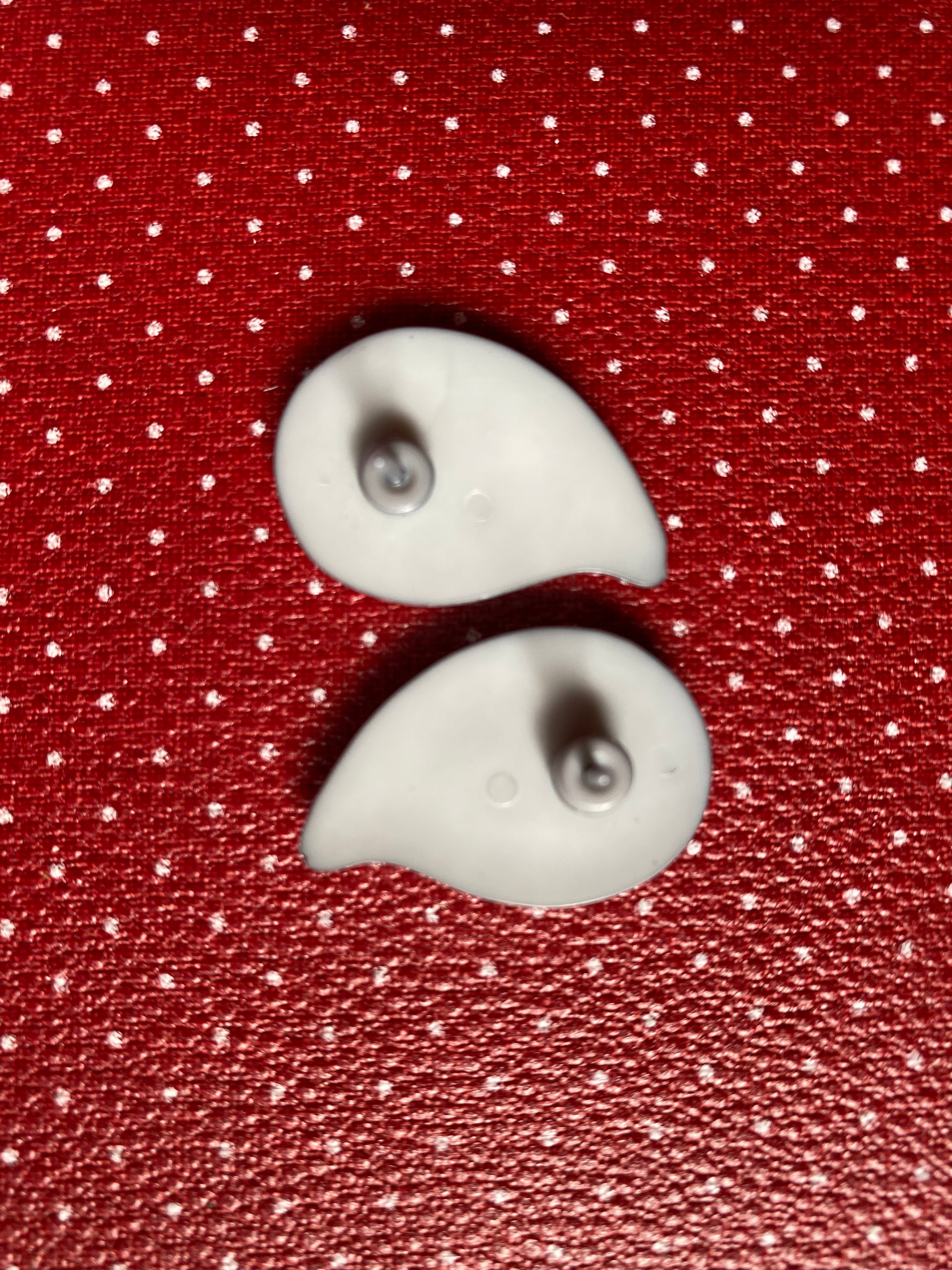 Showing the back of the earrings on a red fabric background with white polka dots