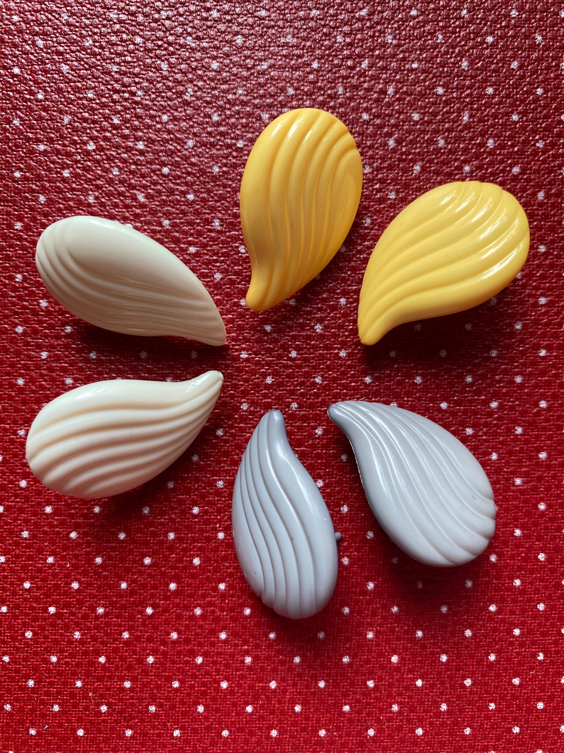 Authentic 80s earrings in yellow, white, and gray on a red retro polka dot background