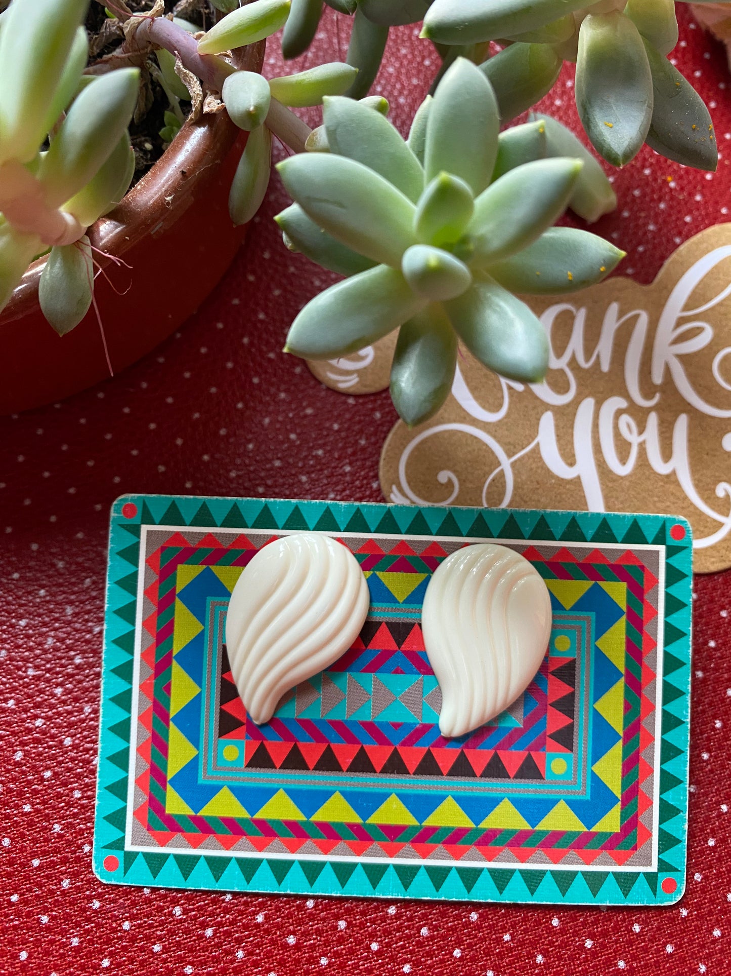 Pair of white authentic 80s shell-shaped earrings on a colorful card with a 'thank you' message in the background. 