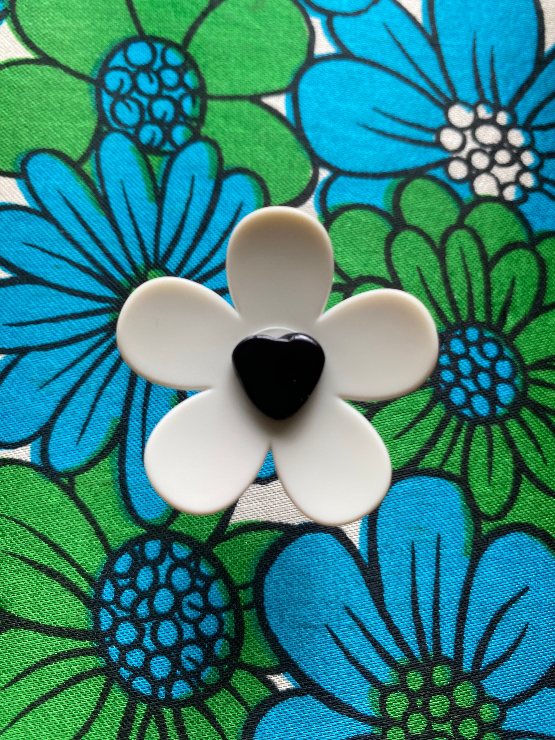 Floral-patterned retro fabric with a white daisy flower featuring a black heart center.