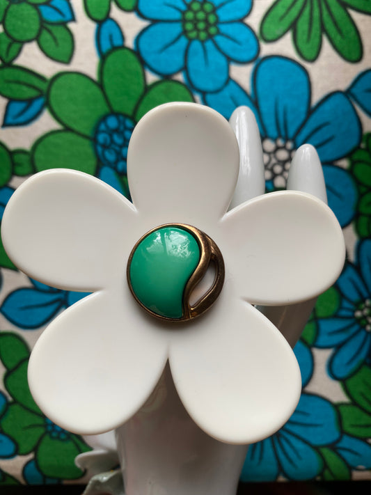 White upcycled daisy flower ring with green center on a floral-patterned background