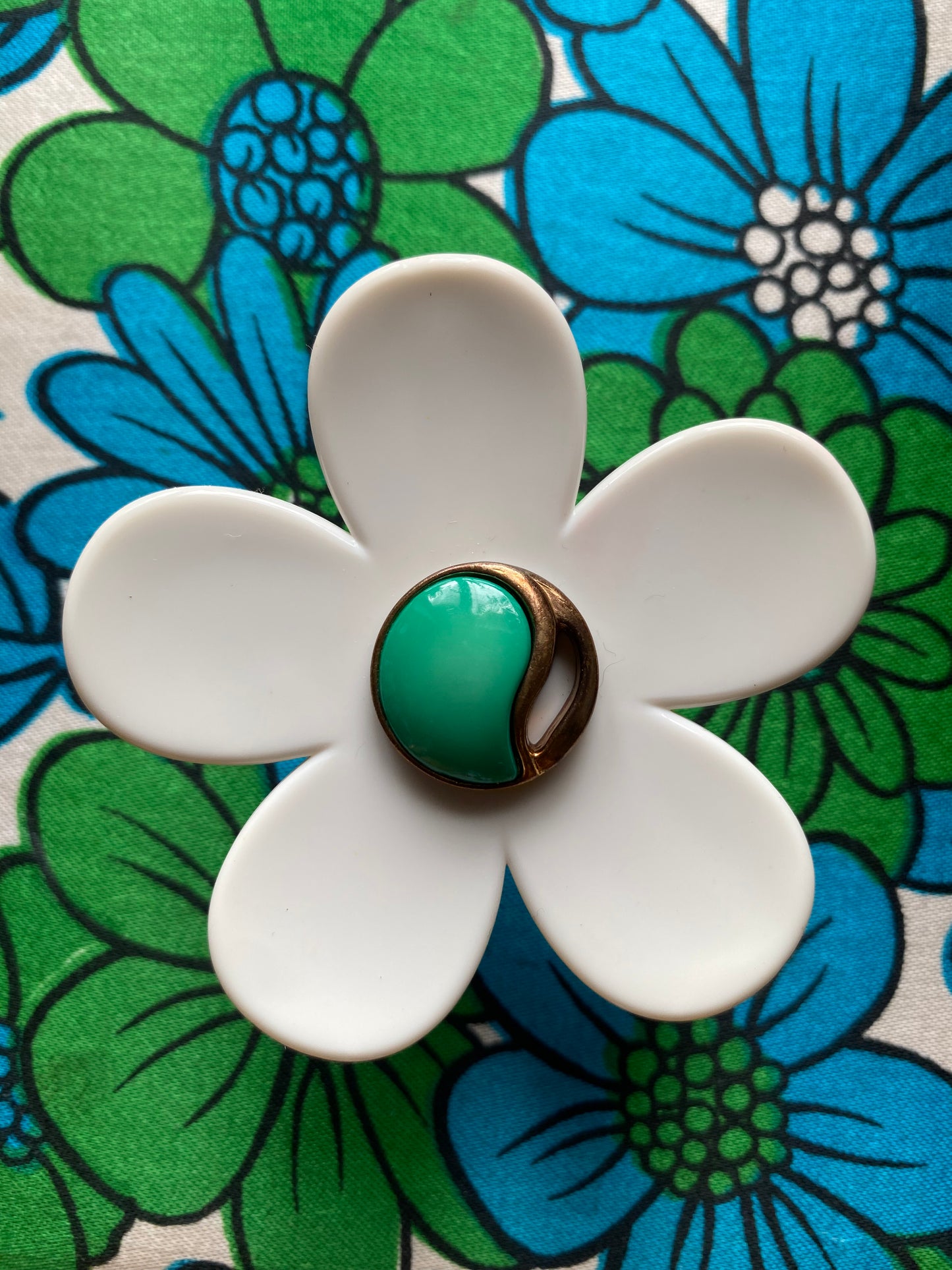 Handmade White daisy flower-shaped ring with a green center on a floral background