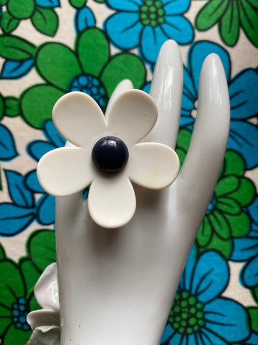 White handmade daisy flower on a hand with a floral retro patterned background