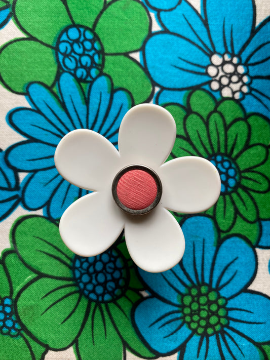 Handmade daisy flower-shaped ring with a pink center on a floral background