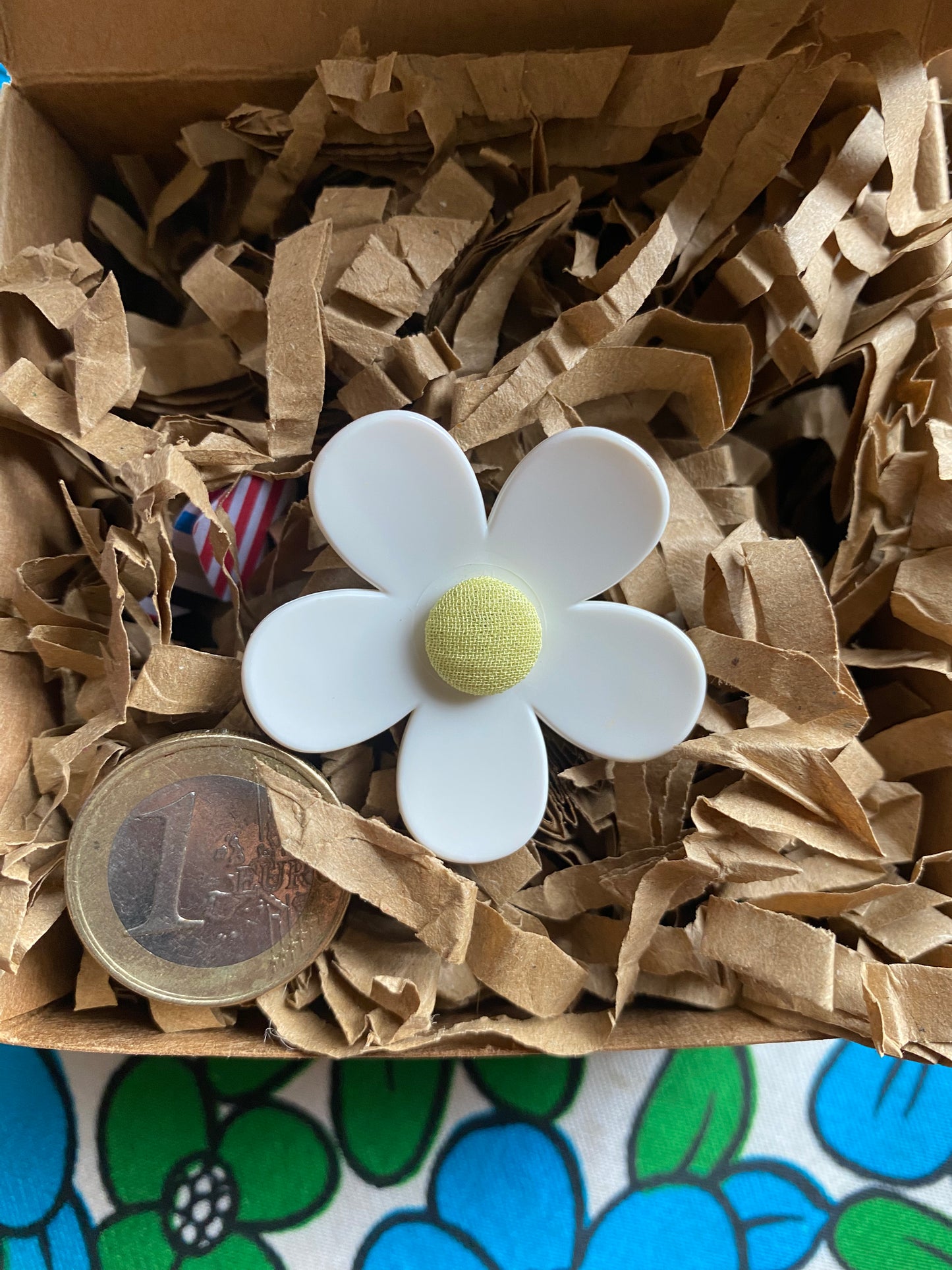 White daisy flower with a yellow center on brown paper inside a giftbox.