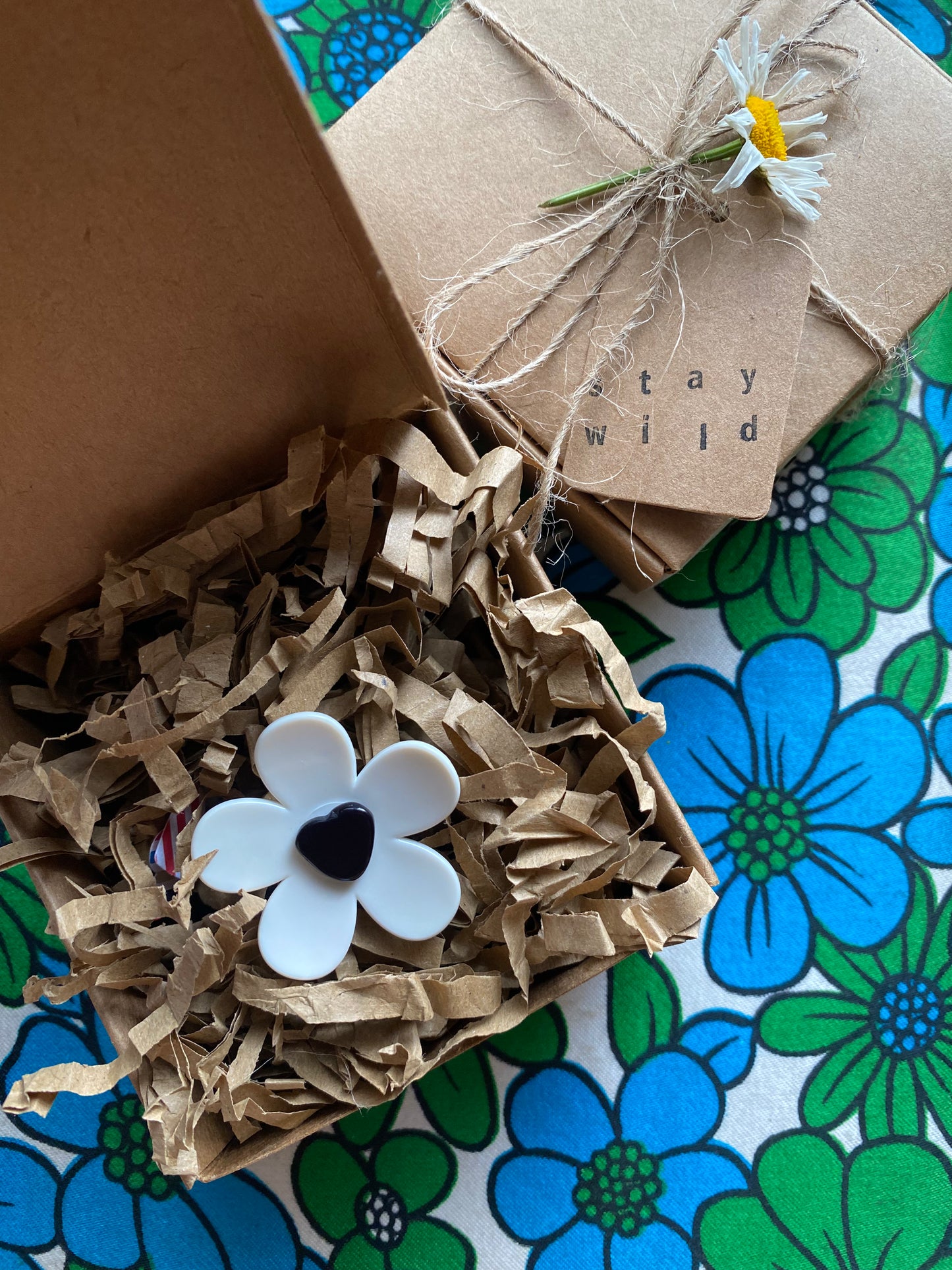 Handmade Daisy Flower-shaped ring in a lovely eco friendly brown paper gift box with 'Stay Wild' text on a floral-patterned surface