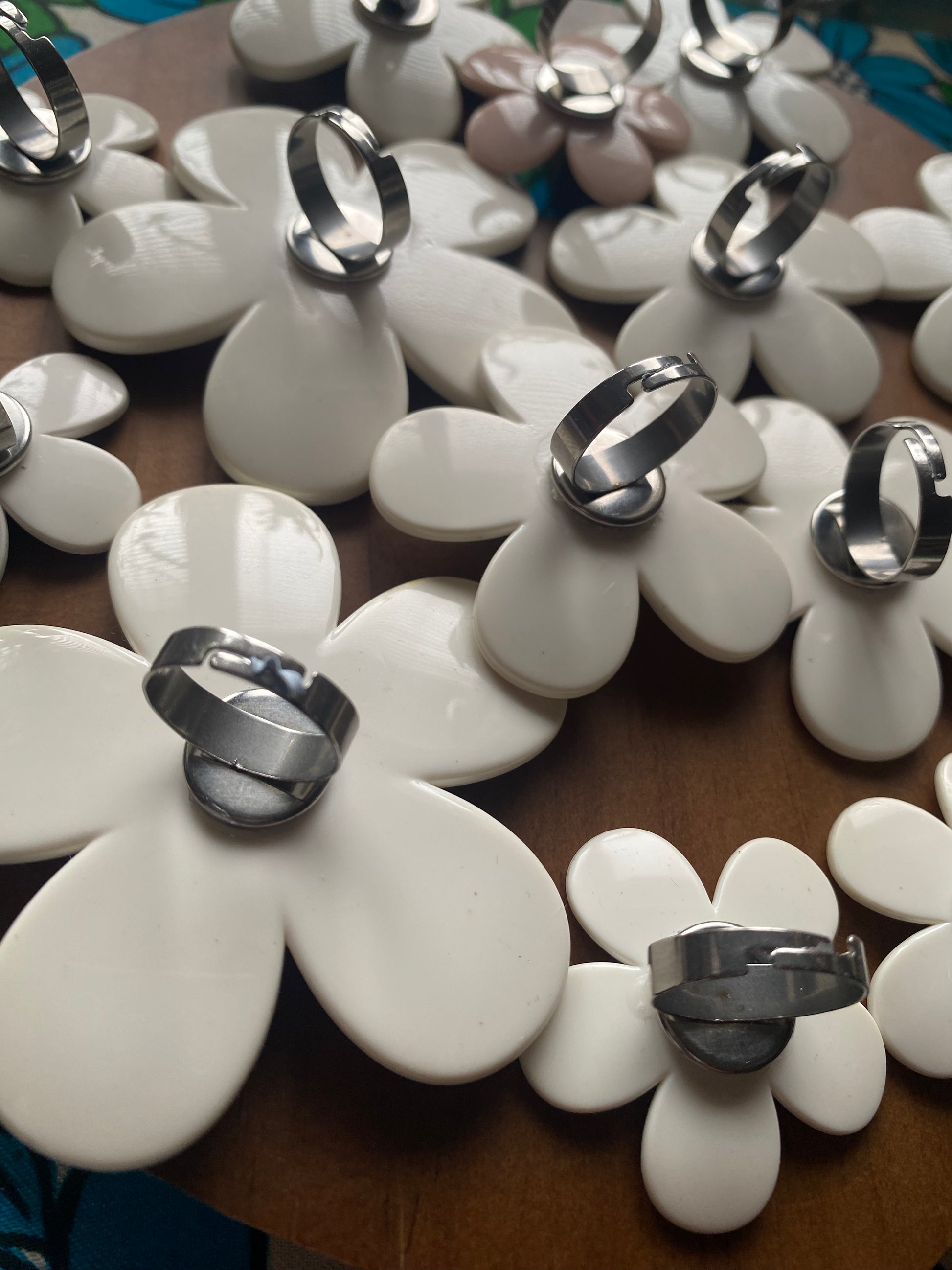 Showing the back of the ring. White daisy flower-shaped  with metal rings on a wooden surface